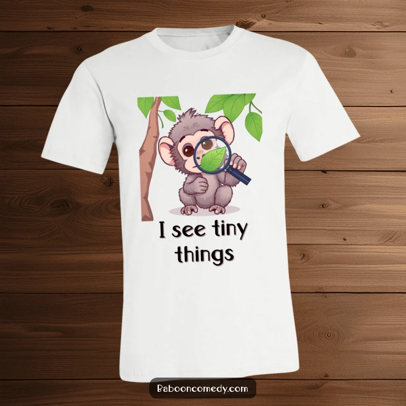 Funny t-shirt showing a curious baboon focused through a magnifying glass at a leaf, embodying intellectual exploration.